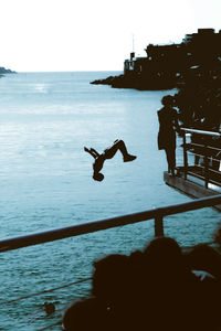 Silhouette man jumping on sea against sky