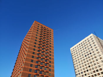 Low angle view of modern buildings against clear blue sky