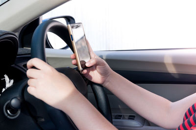 Close-up of woman using mobile phone while driving car