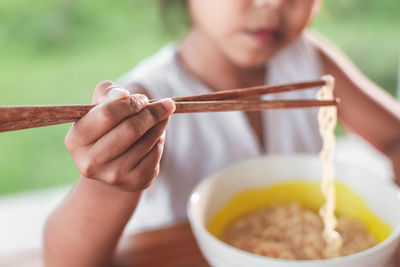 Girl eating noodles at table in public park