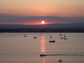 Sailboat sailing in sea at sunset