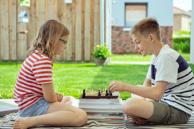 Side view of boy sitting on boys playing outdoors