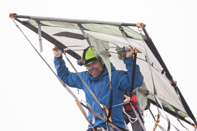 Portrait of rock climber carrying portaledge above head.