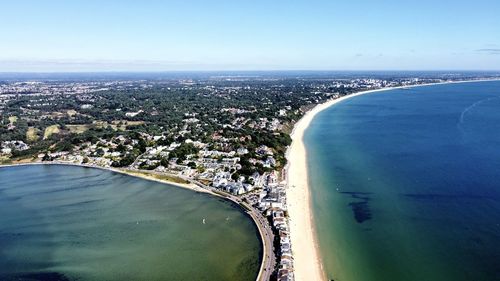 Aerial view of city by sea against sky