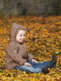 Smiling cute boy sitting on leaves at park