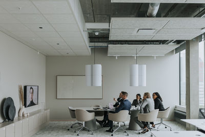 Multiracial business colleagues discussing strategy through video conference in board room