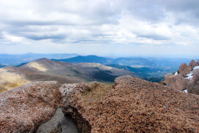 Rock and mountains against cloudy sky