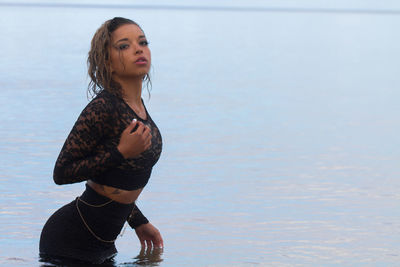 Beautiful young woman standing against sea