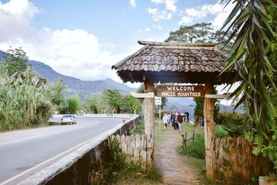 Road amidst trees and buildings against sky