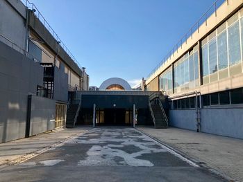 Empty footpath amidst buildings against clear blue sky