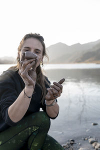 Woman putting mud on hands and face while enjoying outdoors in nature.