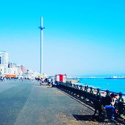 People by sea against clear blue sky