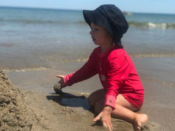 Full length of girl playing with sand at beach