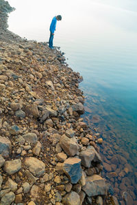 Low section of man standing on pebbles at beach