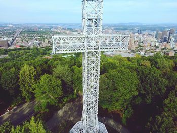 Metallic cross by trees on land in city