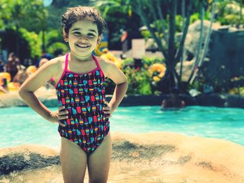 Portrait of smiling girl standing by swimming pool