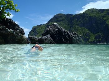 Man swimming in sea against mountain