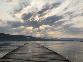 Pier over lake against sky during sunset