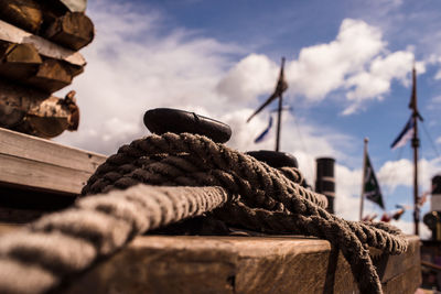 Close-up of rope tied on wood against sky