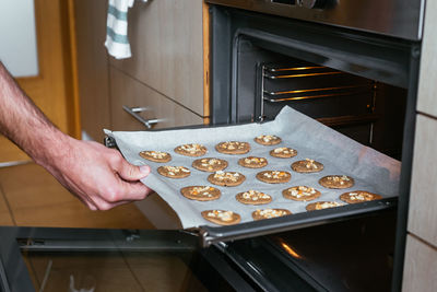 Young man putting the home-made cookies in the oven