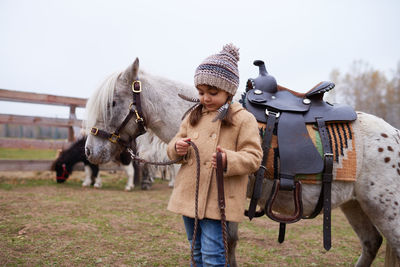 Child with pony in horse paddock