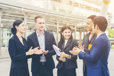 Business colleagues discussing while standing on footpath in city