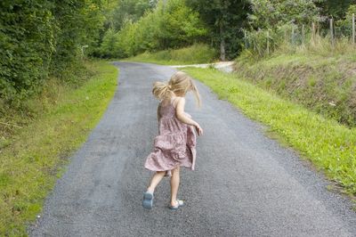 Rear view of girl walking on road