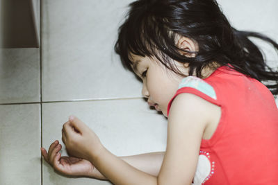 High angle view of girl lying on tiled floor at home