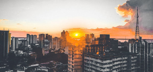 Buildings in city against sky during sunset