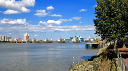 View of city at waterfront against cloudy sky