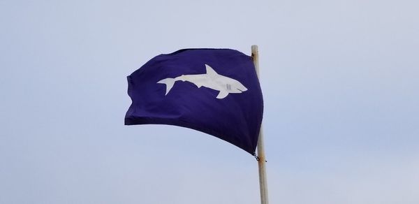 Low angle view of flag against clear blue sky