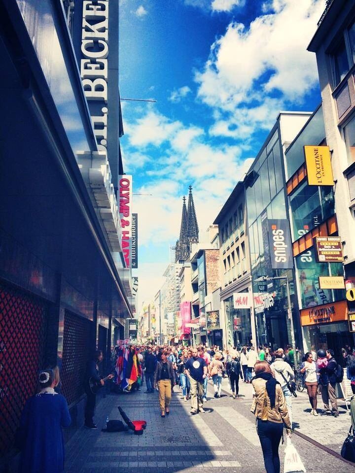 architecture, building exterior, built structure, large group of people, city, street, person, city life, men, lifestyles, walking, sky, city street, crowd, leisure activity, road, the way forward, building, outdoors