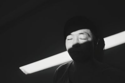 Mature man with closed eyes against wall in sunlight