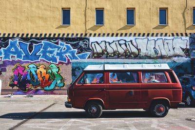 Van on street against graffiti on building during sunny day