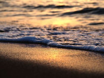 Surface level of sandy beach against sky during sunset