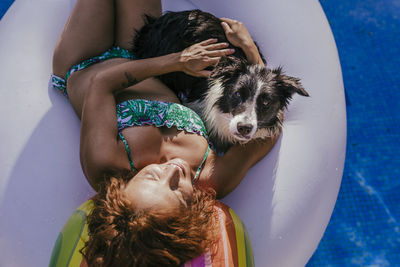 High angle view of woman with dog on inflatable ring in swimming pool