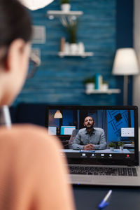 Side view of young woman using laptop at table