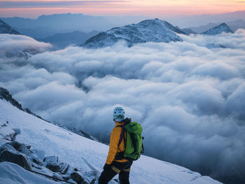 Mountaineer enjoying views during sunrise in high alpine scene above clouds, austrian alps, europe
