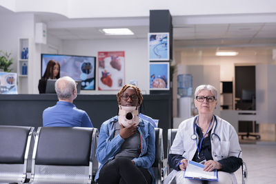 Portrait of female friends using mobile phone while sitting at airport