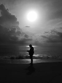 Silhouette woman standing on beach against sky