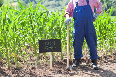 Low section of farmer standing by sign at farm