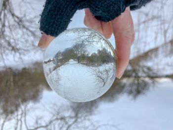 Close-up of hand holding crystal ball on snow