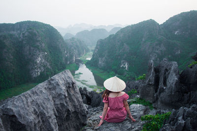 Woman looking at waterfall against mountains