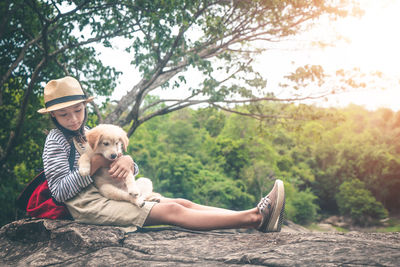 Man with dog sitting by tree against plants