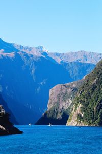 Scenic view of sea and mountains against clear blue sky