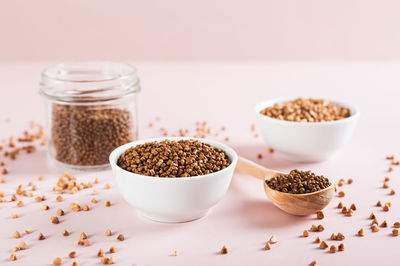 Dry buckwheat tea granules in a bowl, spoon and jar on the table