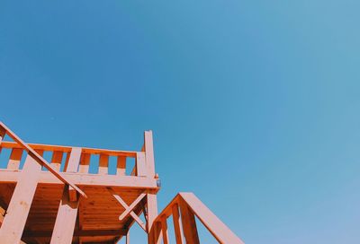 Low angle view of chairs on beach against clear blue sky