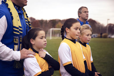 Soccer players standing with trainers while looking at match