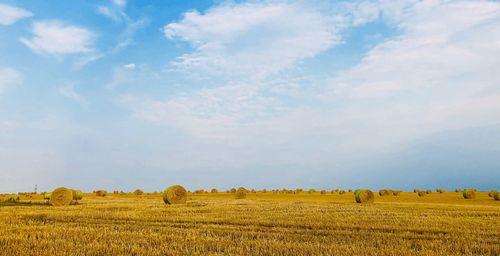 Hay bales on field against sky