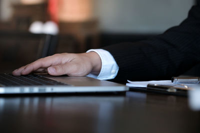 Cropped hand of judge holding hand on laptop on table at office